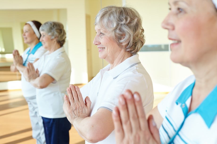 Gruppe älterer Frauen beim Yoga oder Entspannungstraining mit gefalteten Händen.
